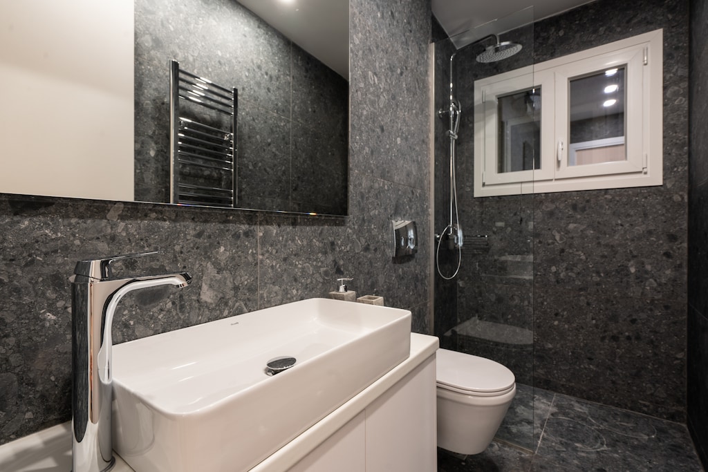 Exceedingly elegant and utterly practical, the marble-clad ensuite bathroom comes with a powerful rain shower