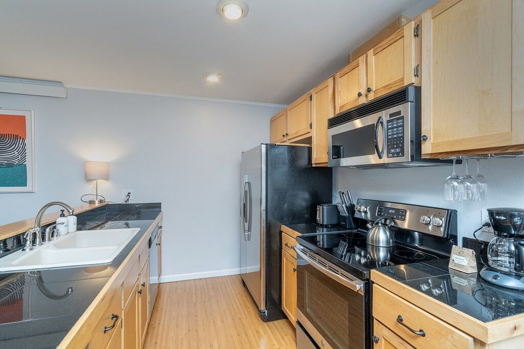 Galley Kitchen with modern appliances including microwave, dishwasher, electric oven.