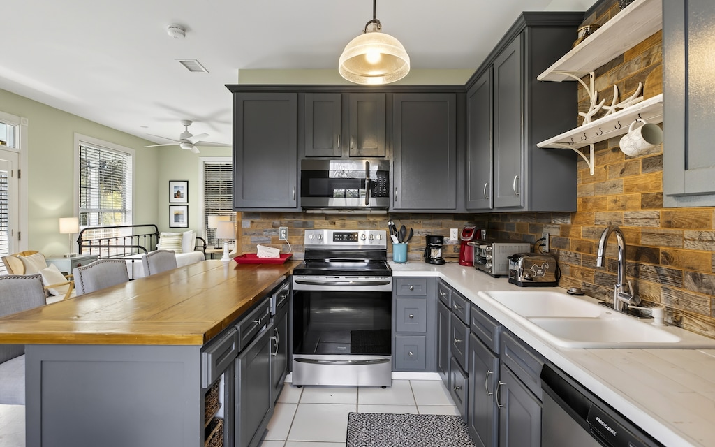 Your fully equipped kitchen features sleek gray cabinets, rustic wood backsplash, and modern stainless appliances for memorable meal prep.