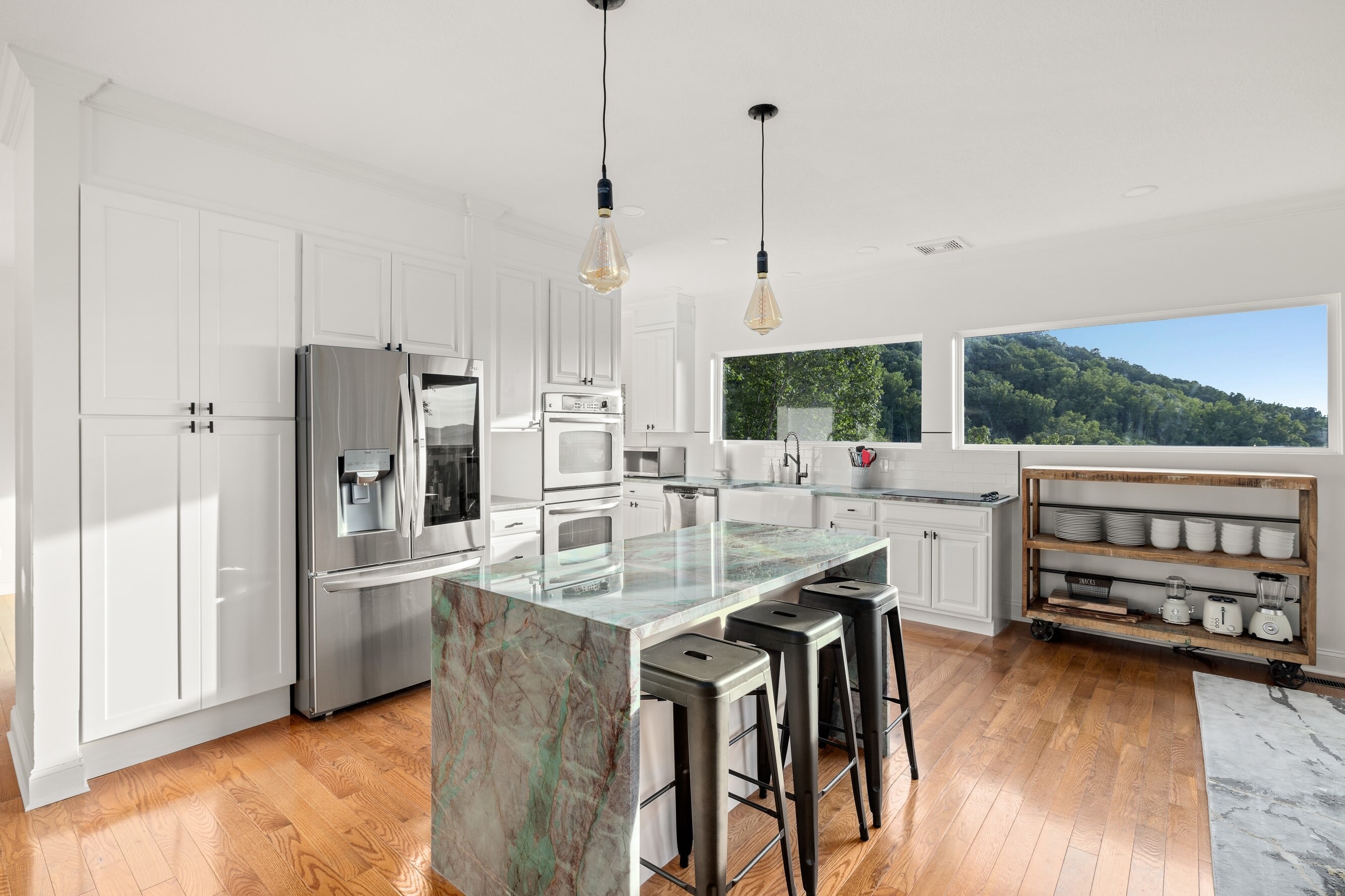 Fully-equipped kitchen with modern appliances and barstool seating at the island counter.
