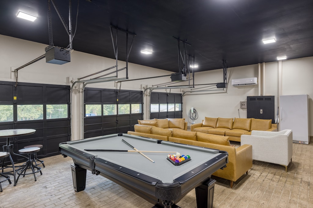 The main home's converted garage game room boasts an oversized sitting area, pool table, and shuffleboard table.