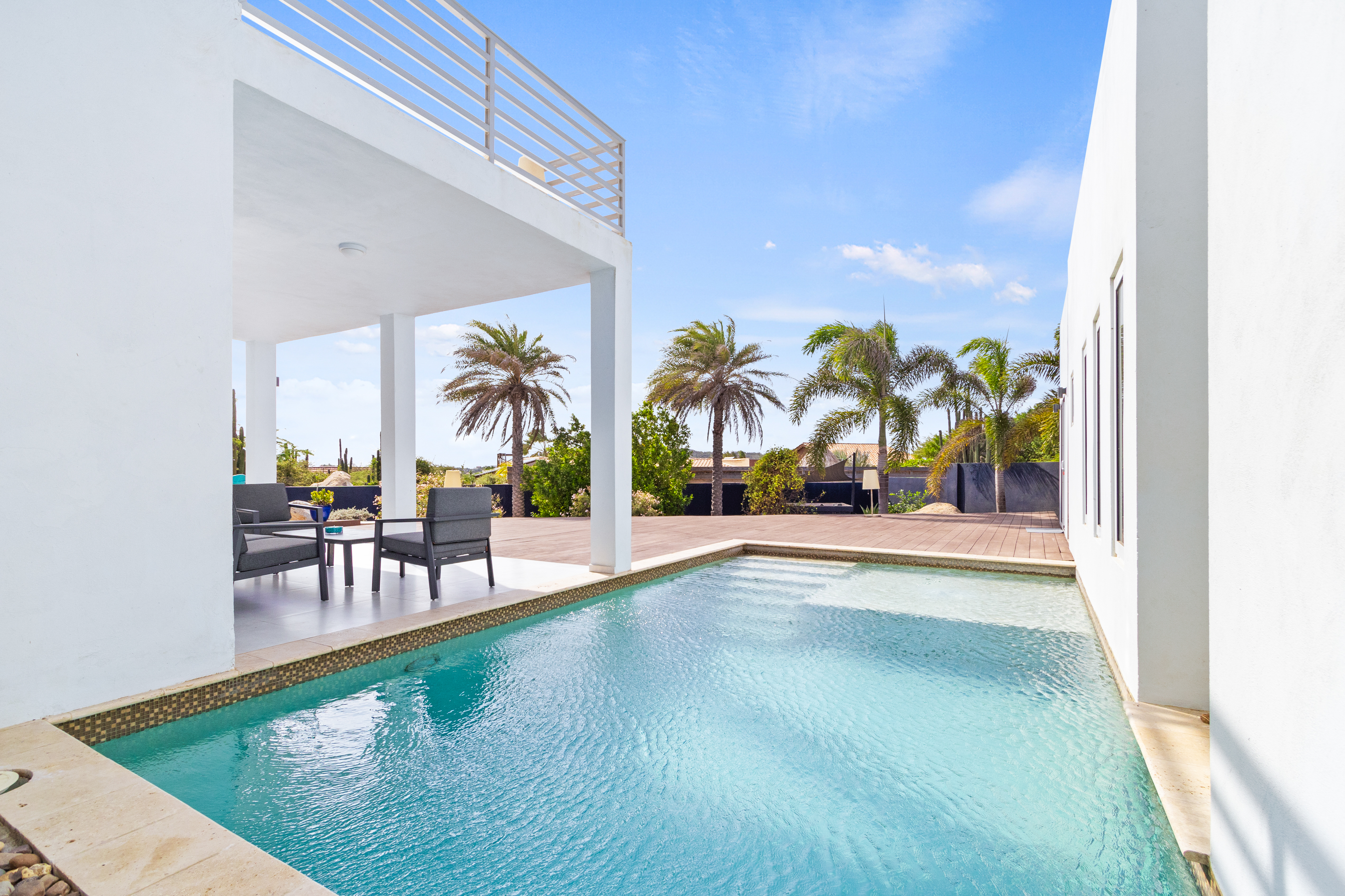 Palatine Pool Area with Tropical Trees view in Santa Cruz Aruba - Crystal-clear pool for refreshing dips - Sleek and stylish pool deck design - Ample shade options for sun-sensitive guests