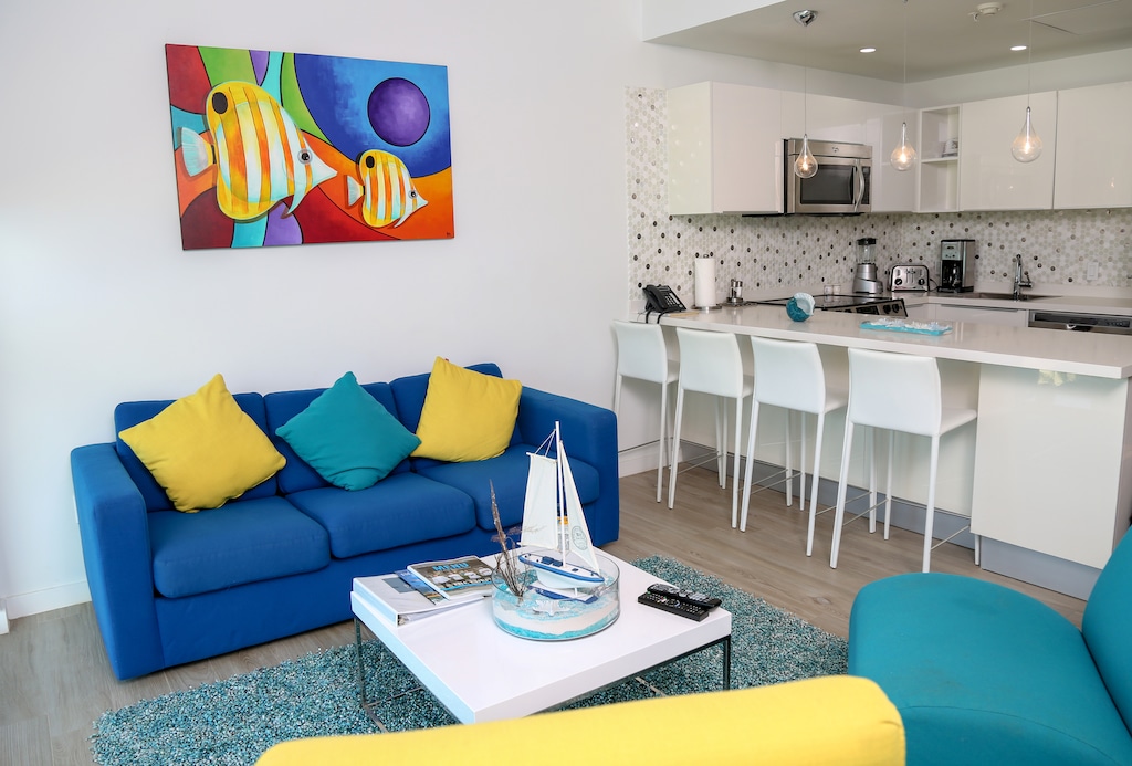 Relax on vibrant seating or gather at the breakfast bar in your bright, open space. The cheerful artwork and pops of color create a welcoming, coastal vibe.