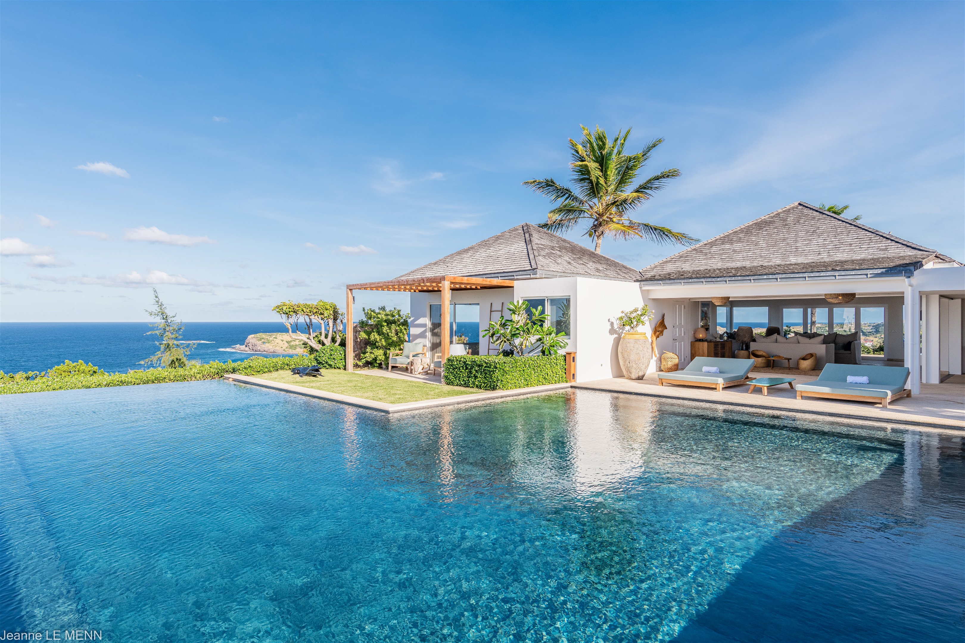 Heated pool surrounded by a spacious sun terrace with deckchairs. An outdoor lounge area with large sofas is on the Terrace facing the spectacular views of Pointe Milou and the ocean. 