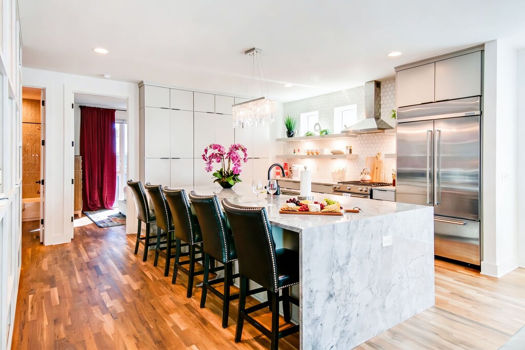 Marble island with bar seating keeps the cook connected to the group, pendant lights casting warmth as everyone gathers around one central hub