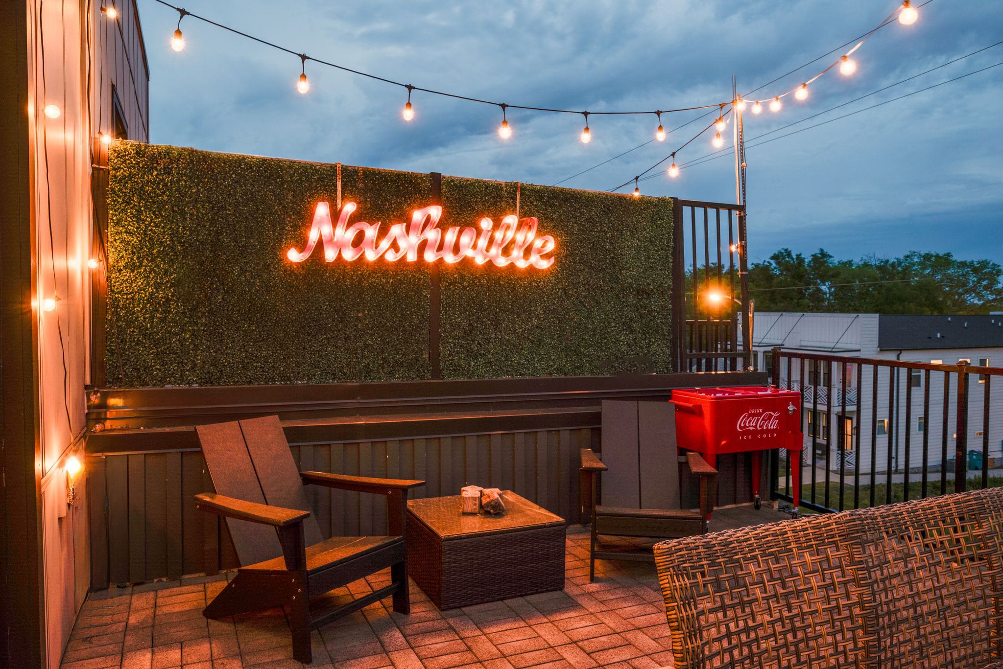Experience Nashville's charm under ambient string lights on our rooftop lounge, a scene set for luxury and leisure. Featuring hearty Adirondack and wicker seating alongside a vibrant "Nashville" neon sign, this outdoor space embodies the spirit of Music City. Whether it's a bachelorette celebration or a fun vacation with friends, sip a cool beverage from the classic Coca-Cola cooler and let the magic of the environment enhance your stay. Perfect for any group getaway, from family trips to friend reunions. 

Ready to create unforgettable memories? Book with Misfit Homes.