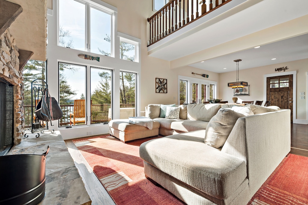 The expansive great room features soaring vaulted ceilings, a stone fireplace, and large windows that flood the space with natural light.