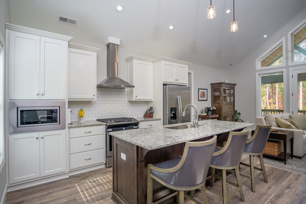 Kitchen with breakfast bar seating for 3, a gas range stove, a dishwasher & 2 types of coffeemakers (Drip-style & Keurig).