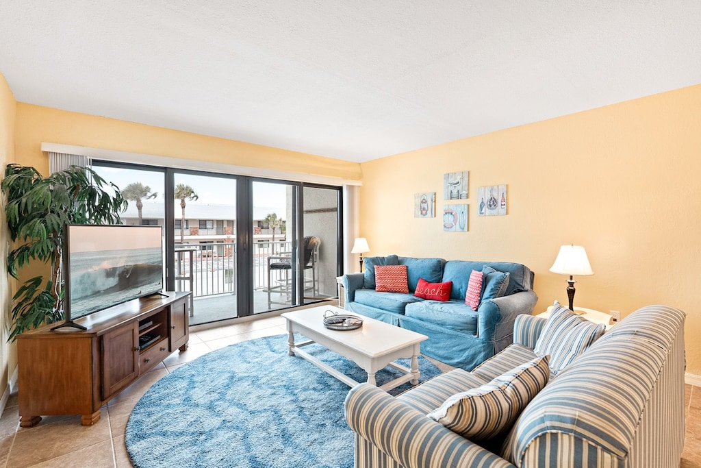 This sun-filled living room opens to the balcony and brings in all the beachy vibes with cozy seating and natural light.
