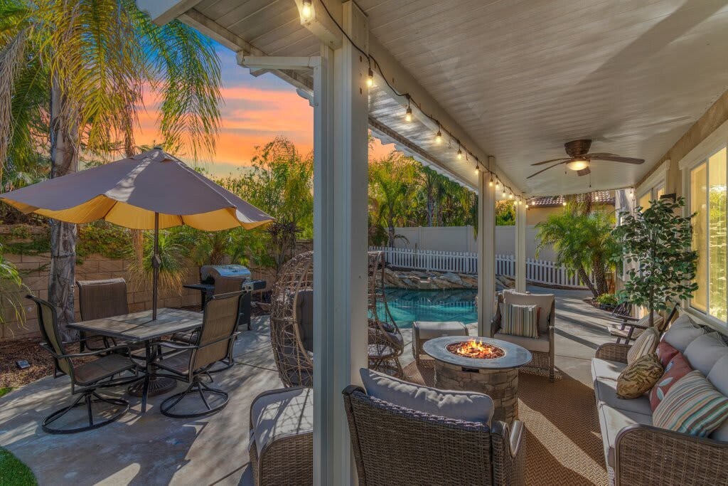 Our little backyard oasis: pool, hot tub, dining table and covered seating space with fire pit table.