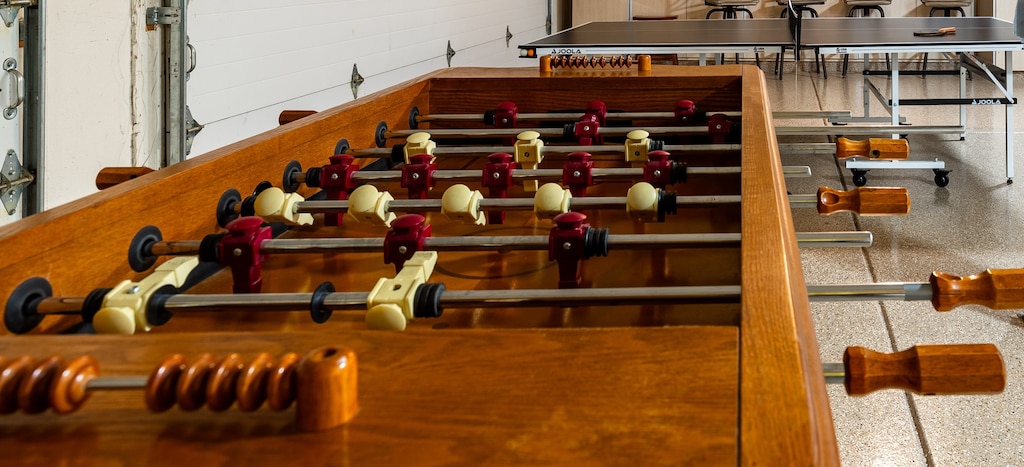 Foosball table and ping pong table in garage for game time.