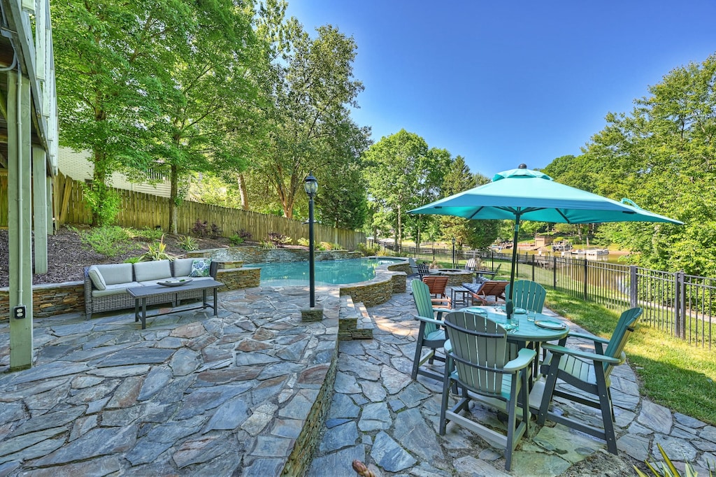 Bar top table with shade, pool loungers and Adirondack seating on the pool deck.