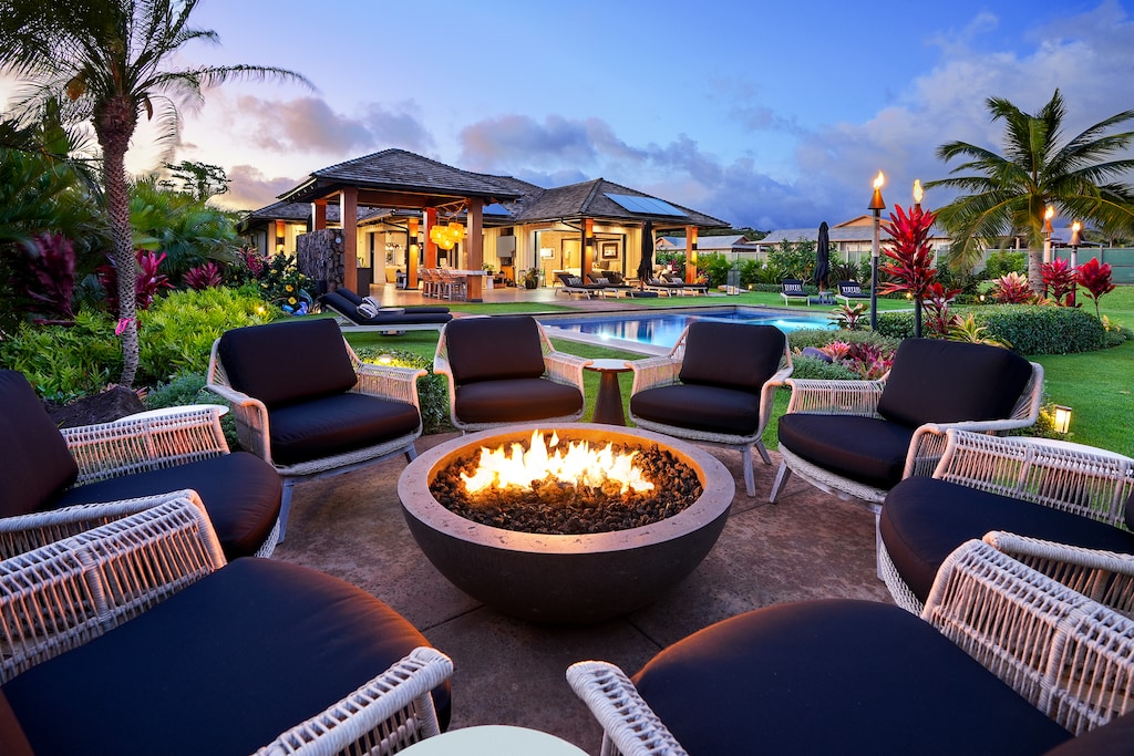Enjoy outdoor firepit elegance, offering views of the pool and lush tropical greenery.