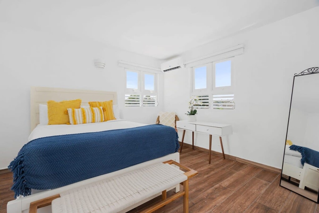 The first bedroom has a queen bed, arm chair, desk, full body mirror and closet.