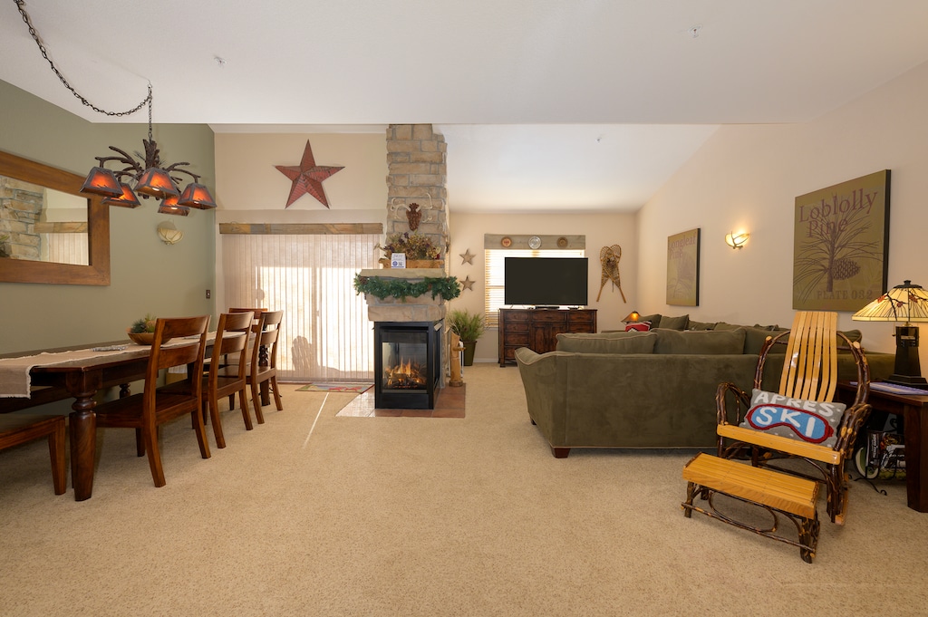 Relax in your spacious open-plan living area with cozy fireplace, comfortable seating, and rustic charm perfect for memorable gatherings.