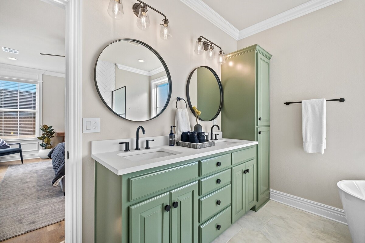 The Master bath has a gorgeous double sink area with green cabinetry and round mirrors.