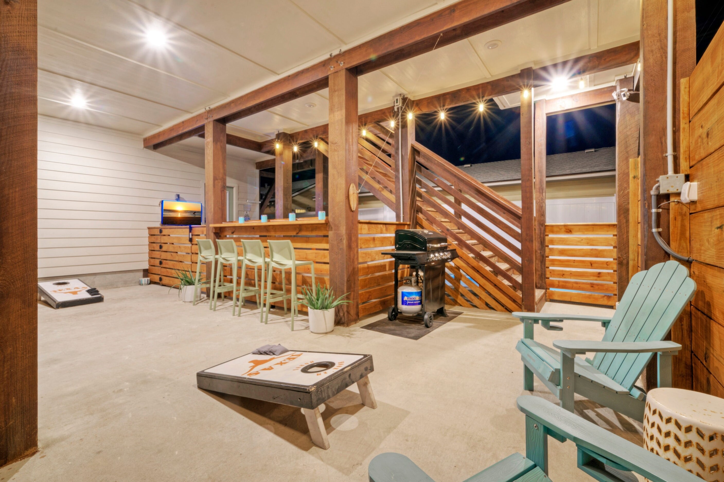 Spacious patio lounge with a bar, cornhole, a grill, and comfortable outdoor seating.