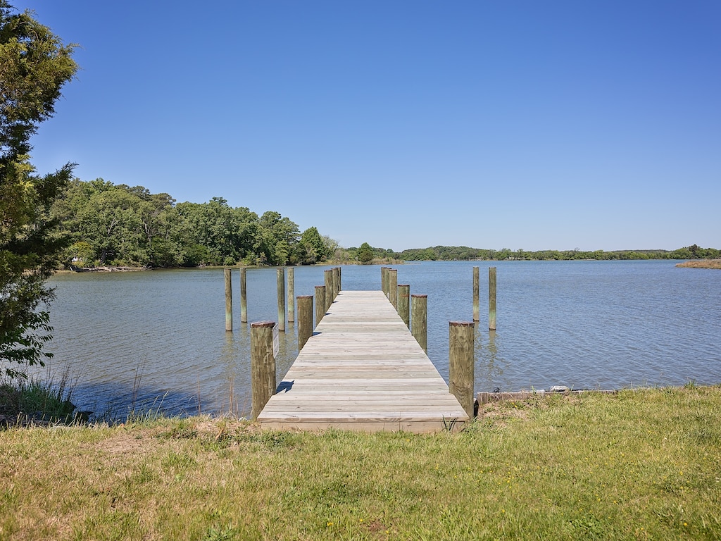 A private wooden dock extends into calm waters, framed by lush greenery and open skies—a peaceful lakeside setting ideal for morning reflection.