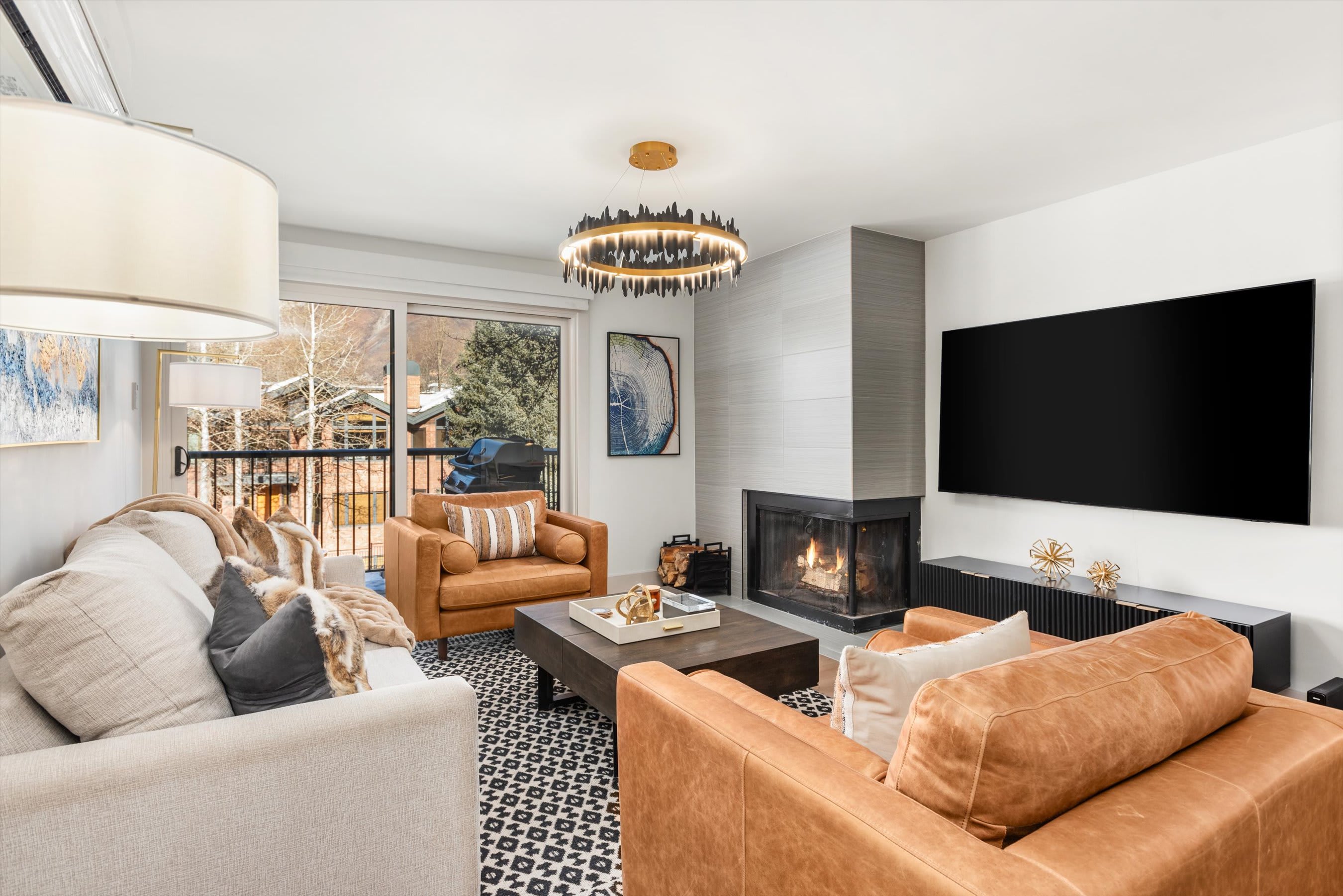 Comfortable living room with wood burning fireplace, sleeper sofa and sliding door to private balcony with view of Red Mountain