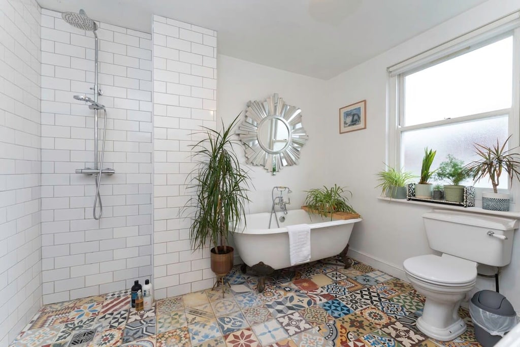 Contemporary fully tiled bathroom with roll topped bath