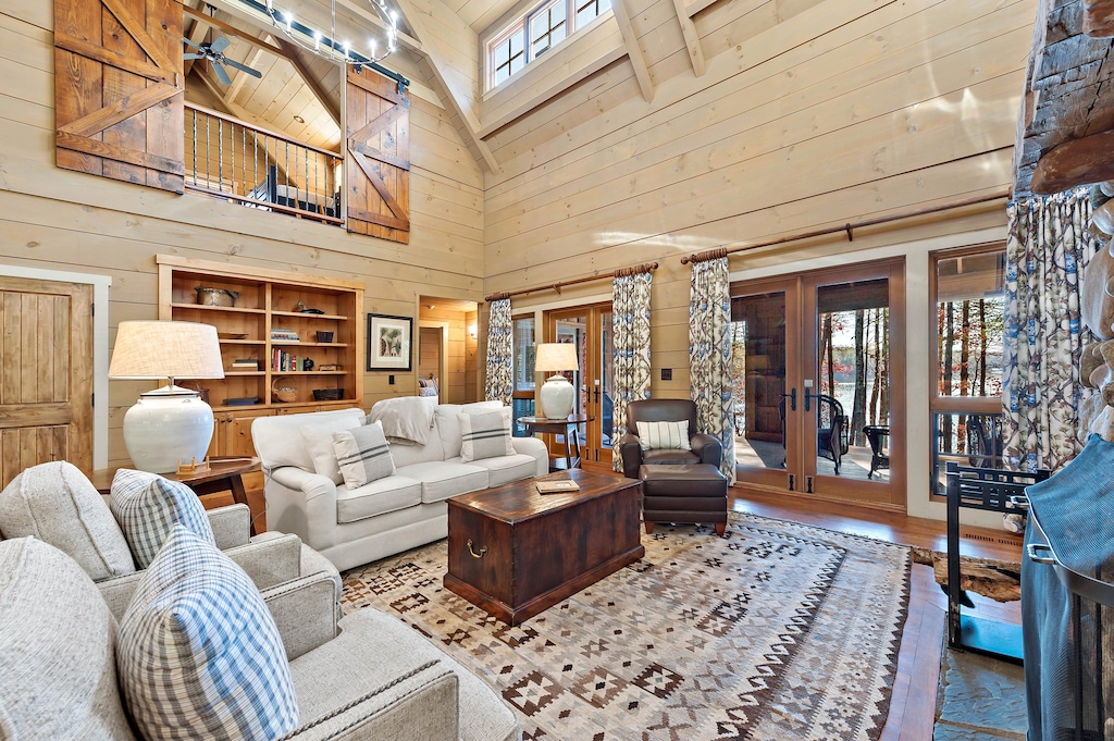 Cozy living room featuring plush seating, wood-burning fireplace, and large windows overlooking the lake for relaxed family gatherings.