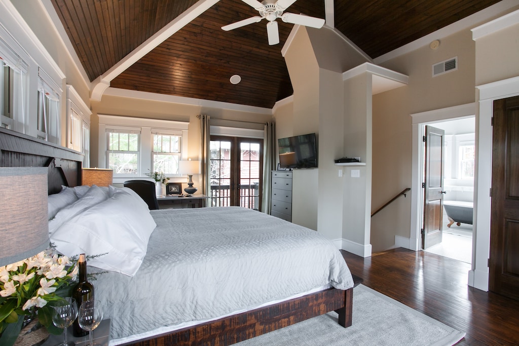 Primary bedroom is beautiful and light-filled with king bed, desk station, private balcony, and en suite bathroom.