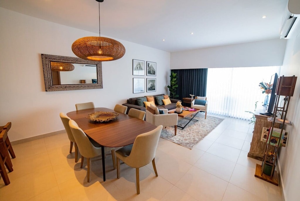 The living room, with an open concept that includes the dining area, the kitchen, the seating and TV area, as well as the balcony overviewing the Tropical garden, the Central Park and the pool.