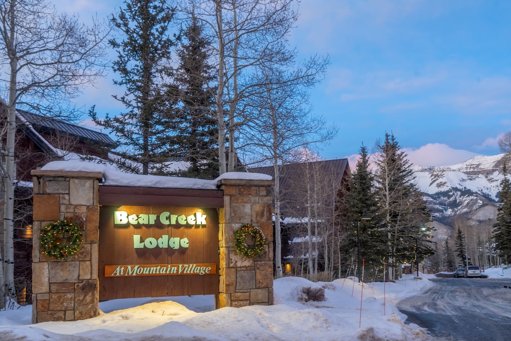 Bear Creek Lodge entrance sign welcomes visitors to this mountain village property during winter evening hours.