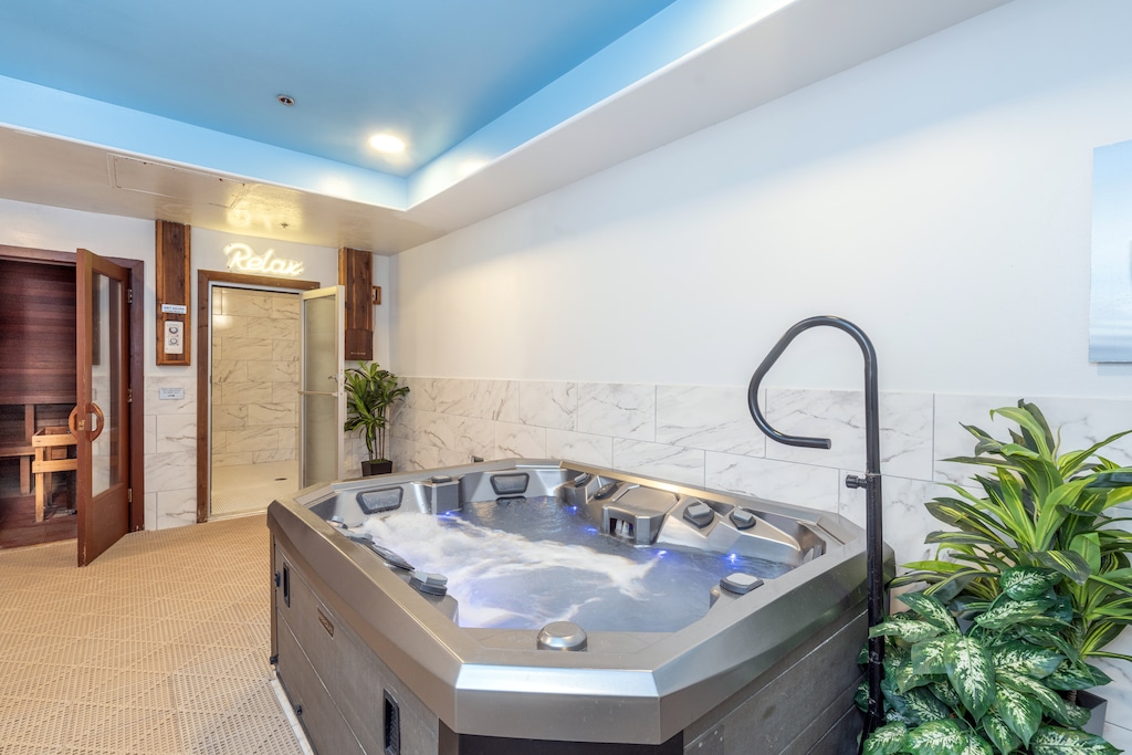 Unwind in your private spa sanctuary with bubbling hot tub, marble accents, and tropical plants creating the perfect relaxation retreat.