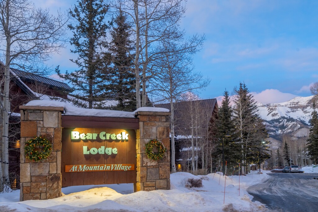 Bear Creek Lodge entrance sign welcomes visitors to this mountain village property during winter evening hours.