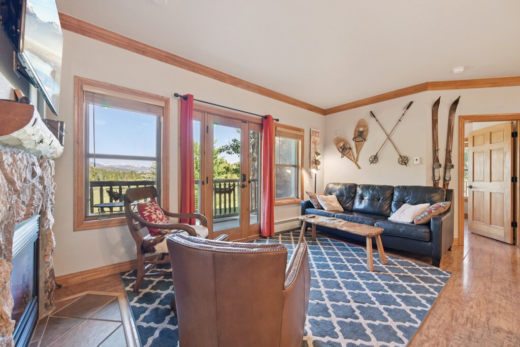 Sunny living area with sleeper sofa, flatscreen TV, gas fireplace, and walk-out deck. 
