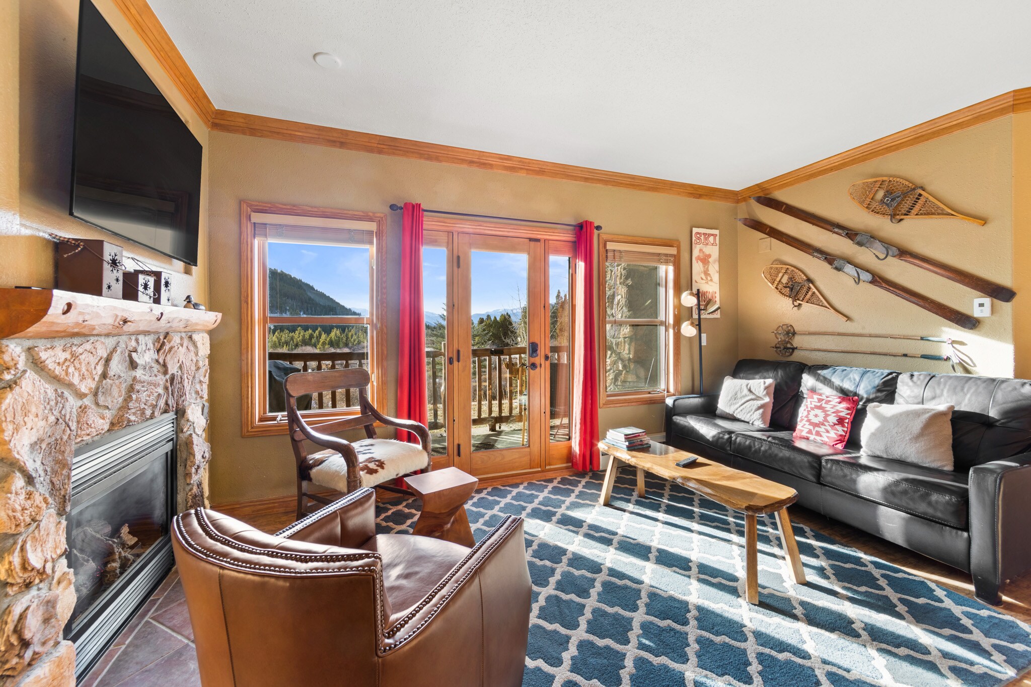 Sunny living area with sleeper sofa, flatscreen TV, gas fireplace, and walk-out deck. 