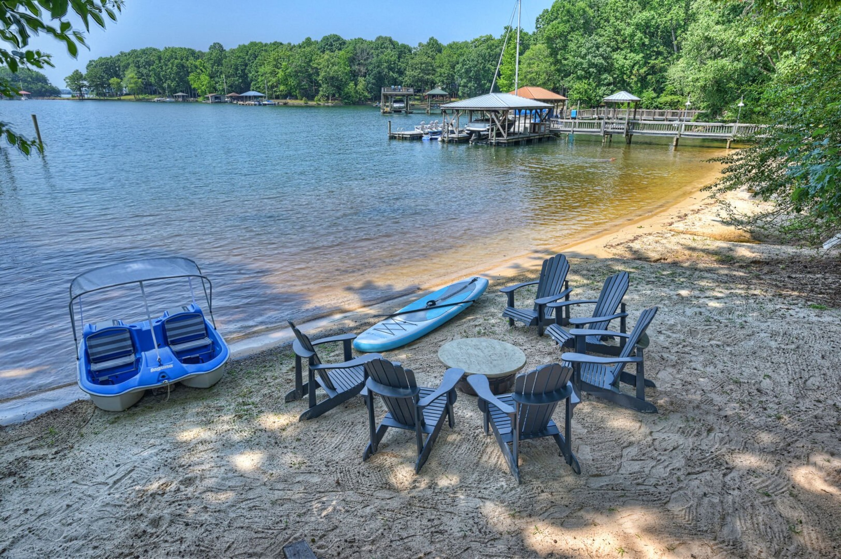 Adirondack chairs surrounding the lakeside fire pit plus a pedal boat.