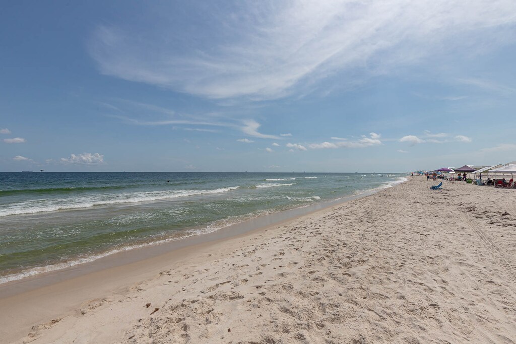 This beachfront view showcases soft sand and gentle waves, perfect for a relaxing day by the water