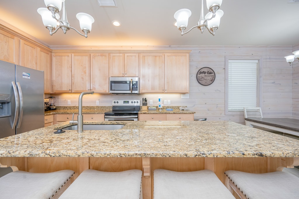 Bright kitchen featuring granite countertops, stainless appliances, and cozy seating at the island