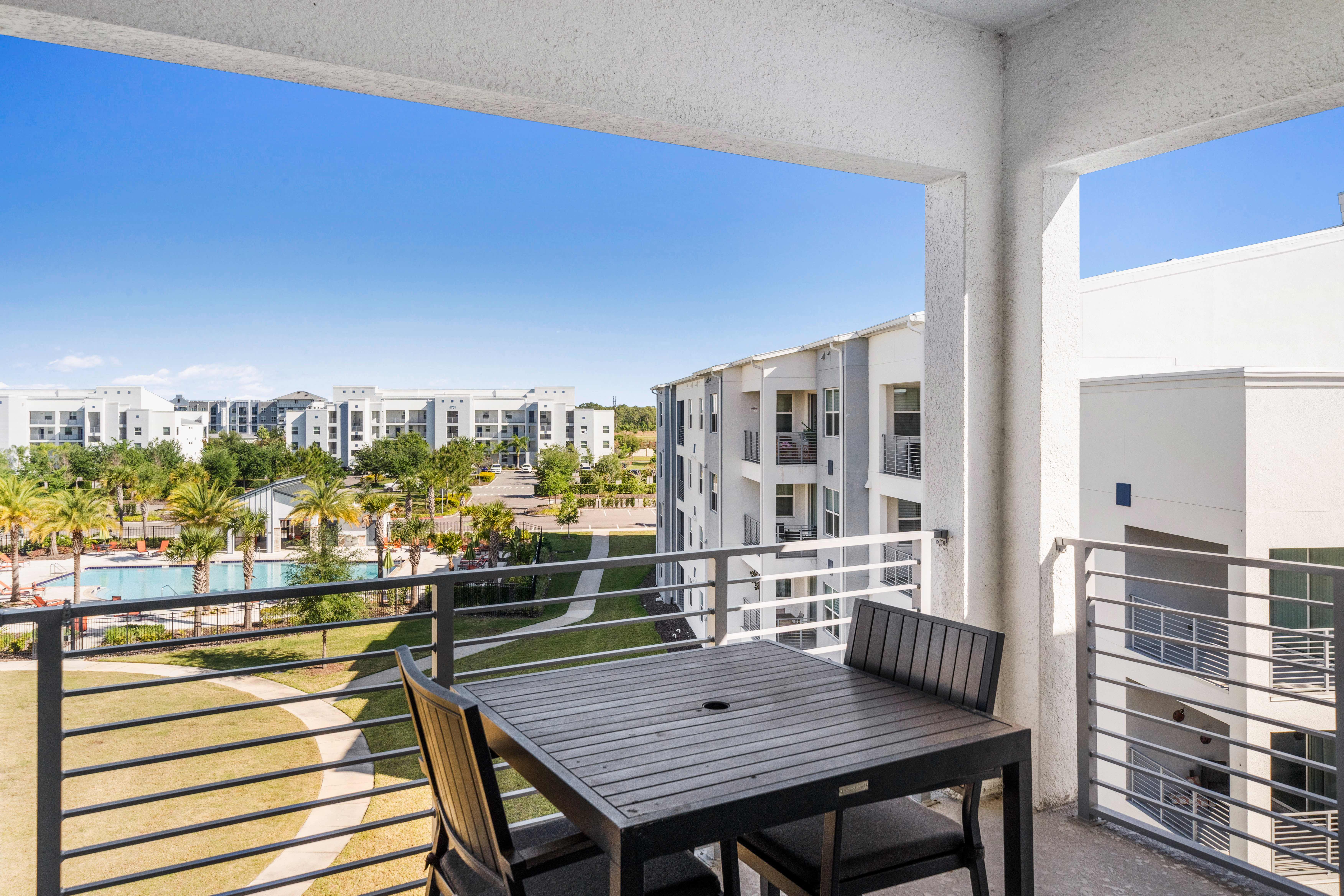 Imposing Private Balcony of the Condo in Kissimmee - Mesmerizing Pool and surrounding views from the balcony - Beautiful 2 Persons Dinning for having coffee in the refreshing atmosphere - Fabulous sitting space