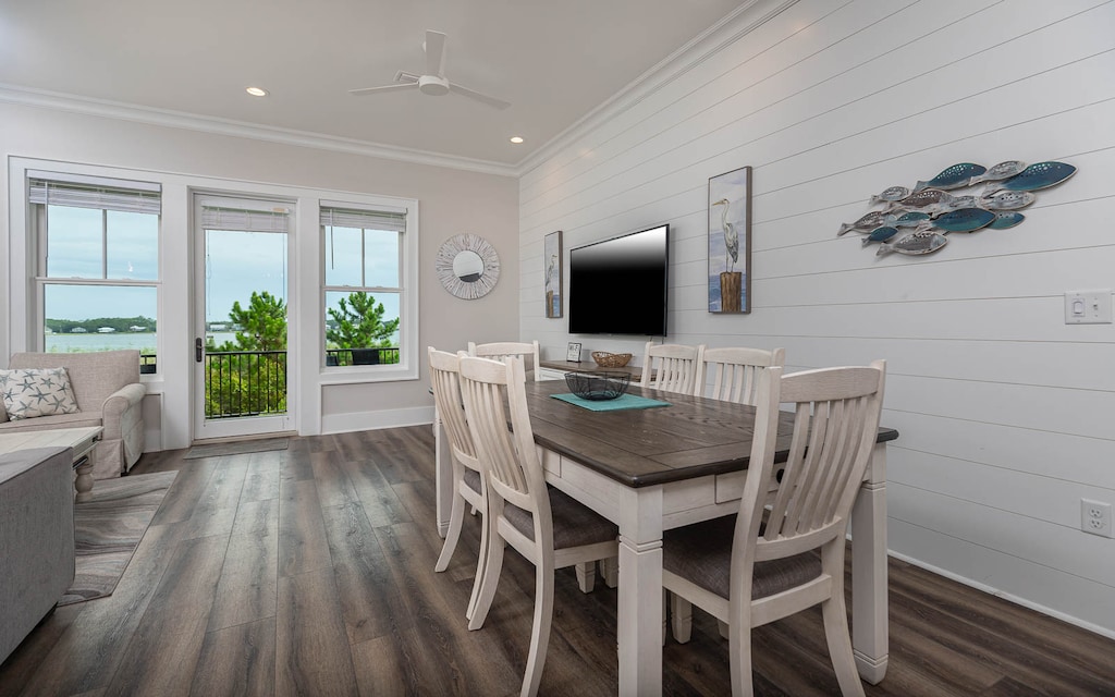 This inviting dining area features a large table, a wall-mounted TV, and a lovely lagoon view through the windows