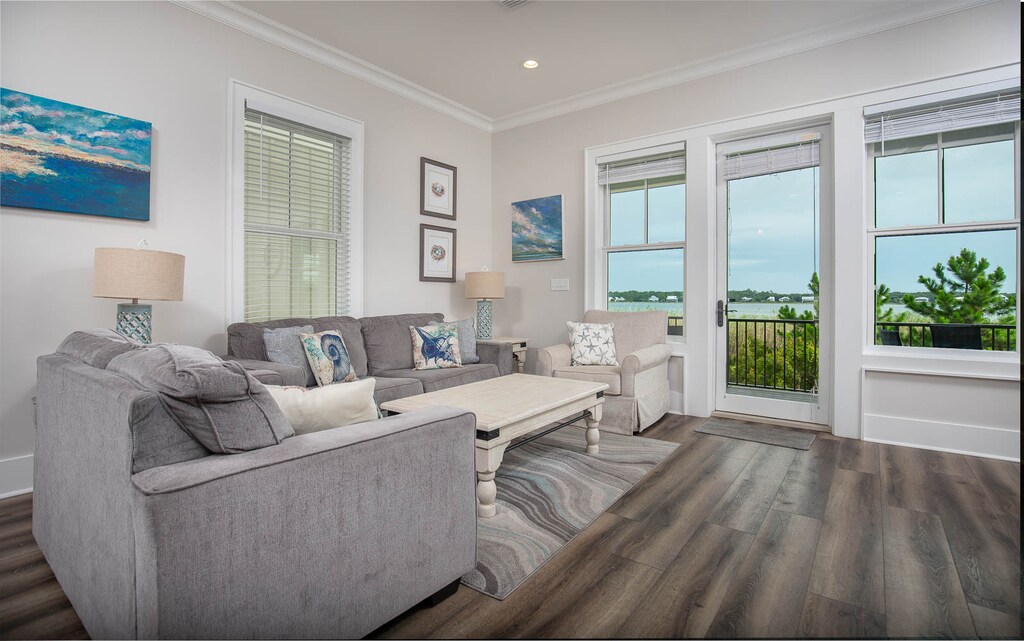 This cozy living area features gray sofas, colorful coastal decor, and a serene lagoon view through large windows