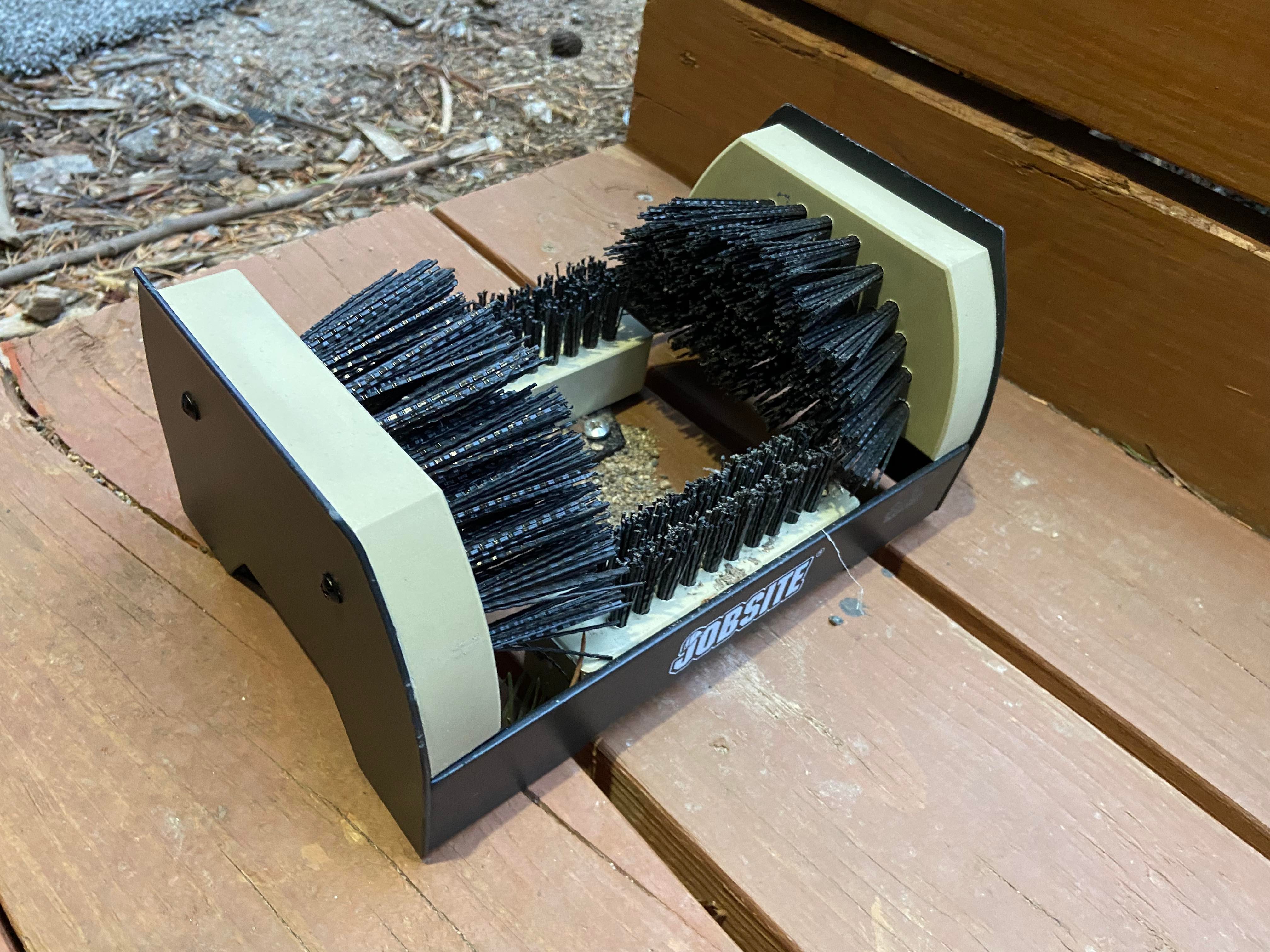 A black brush sitting on top of a wooden deck.