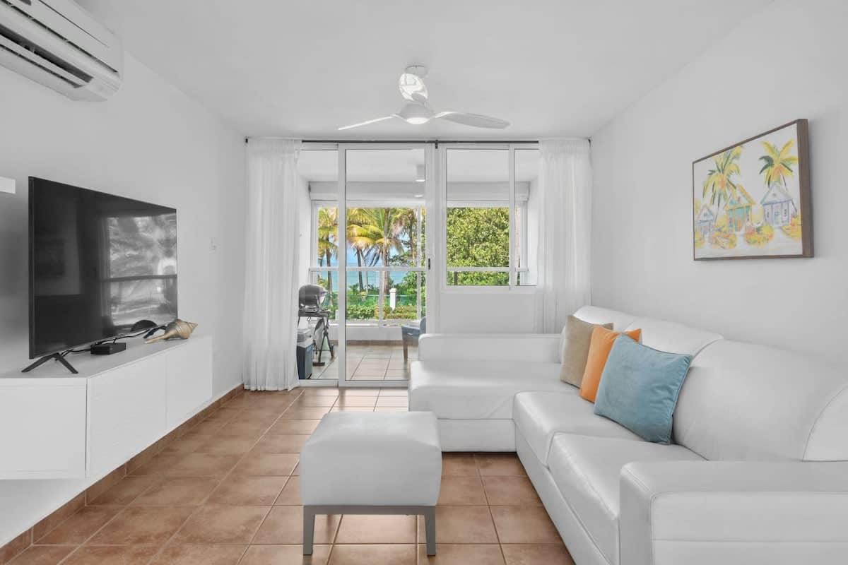 The airy living space with flat screen tv, sofa and beachfront balcony.