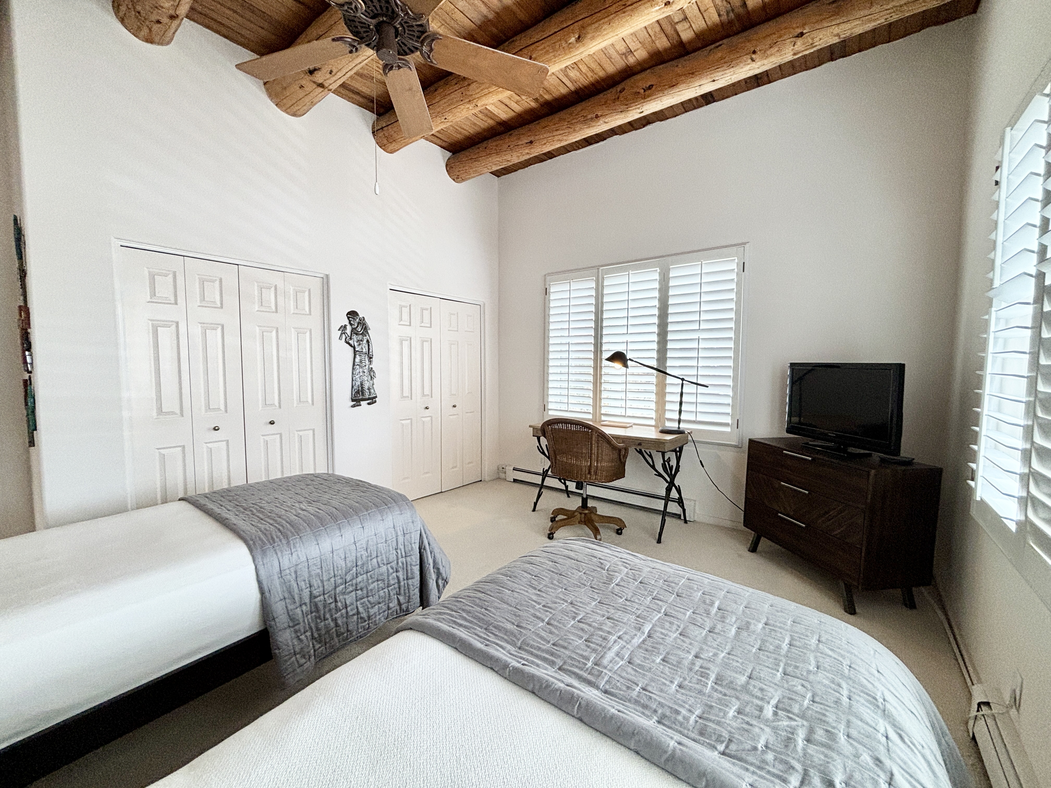 A bedroom with two beds and a ceiling fan.