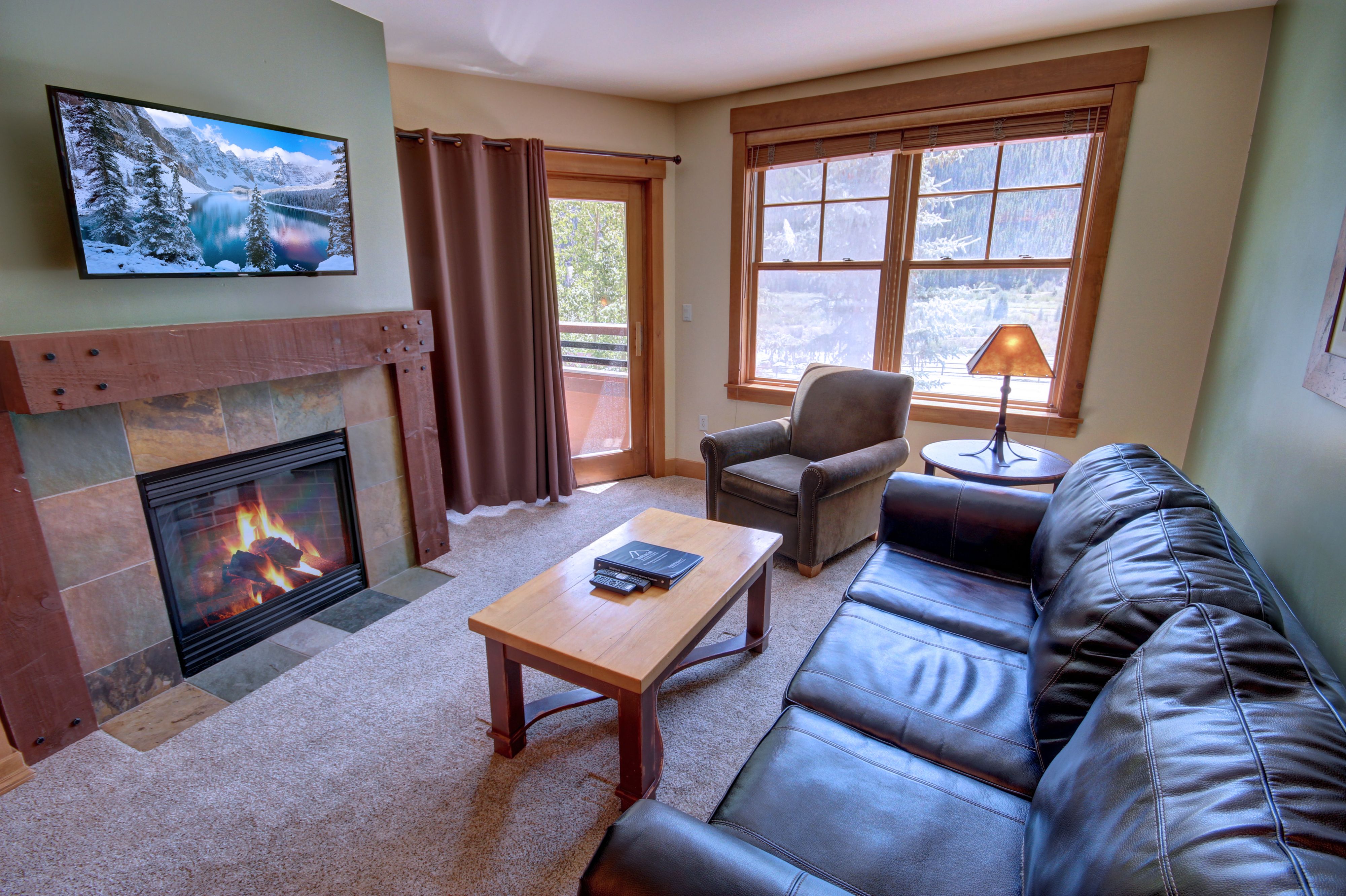 A living room with lots of natural lighting and a TV and fireplace for cold days