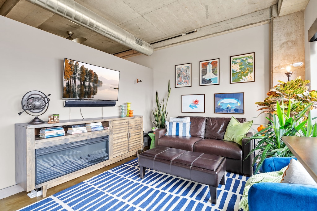 Unwind in your stylish living space with exposed concrete ceilings, cozy fireplace, and modern entertainment setup for perfect evenings.