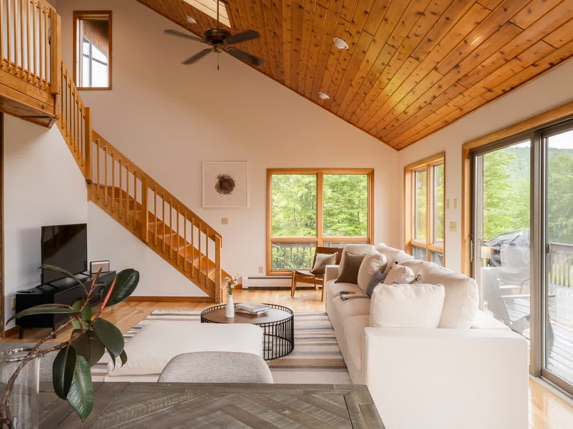 The interior of the home is beautifully designed with bright and airy spaces, including the living room, which contains cathedral ceilings and panoramic mountain views.