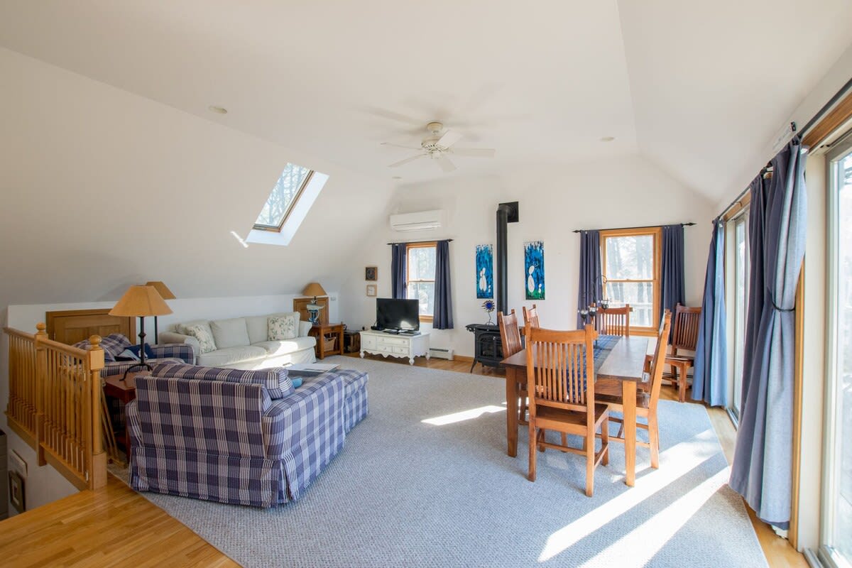 living room with couch, tv, wood stove and lazy boys looking into dining room with table