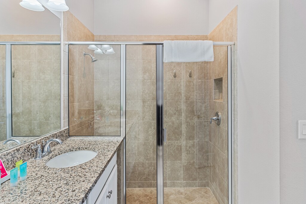 Polished Bathroom of the Townhouse in Davenport Florida - Glass-enclosed walk-in shower area - Chic vanity with upscale lighting - Elegant bathroom with lush fixtures and finishes