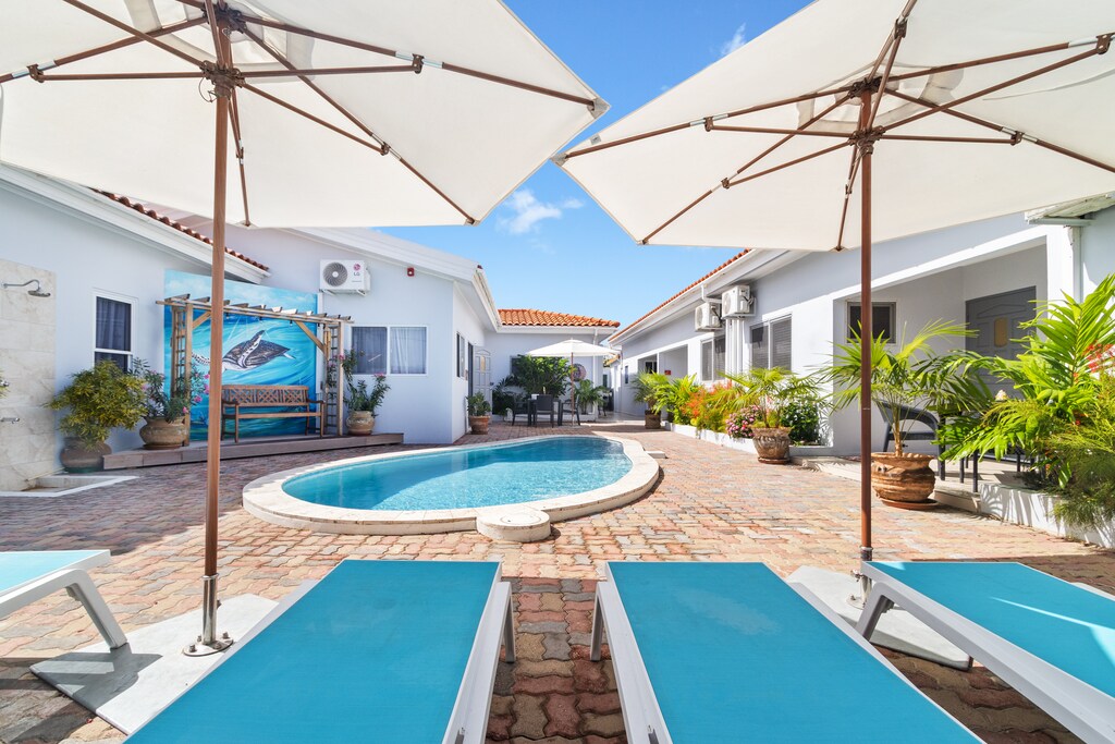 Charming Shared pool Area of the Apartment in Noord Aruba - Lounge in tranquility by the sparkling waters - Dive into a refreshing poolside escape - Comfortable Lounge chairs