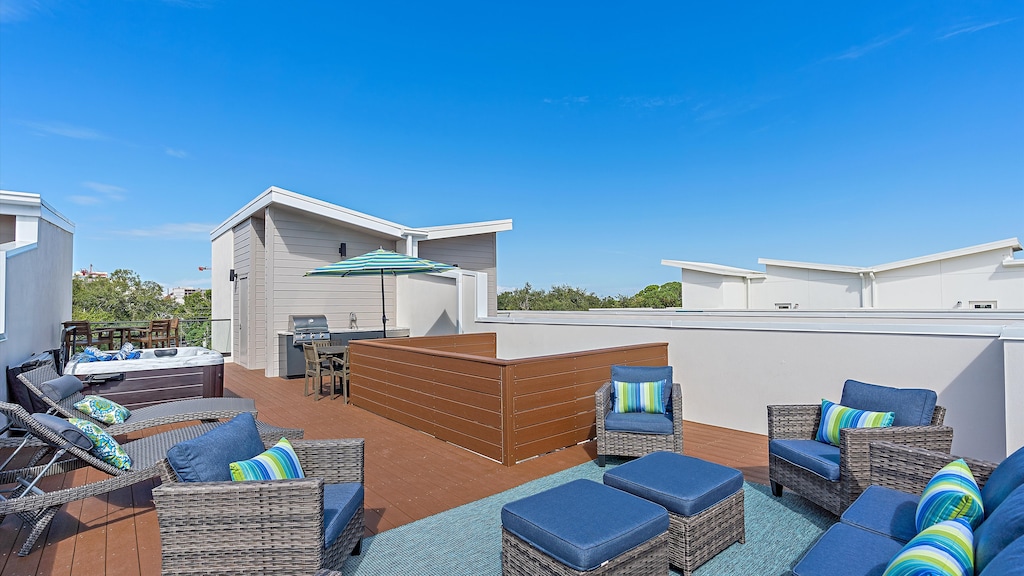 Rooftop patio with wicker furniture, blue cushions, striped pillows, a rug, a table with chairs, and an umbrella.