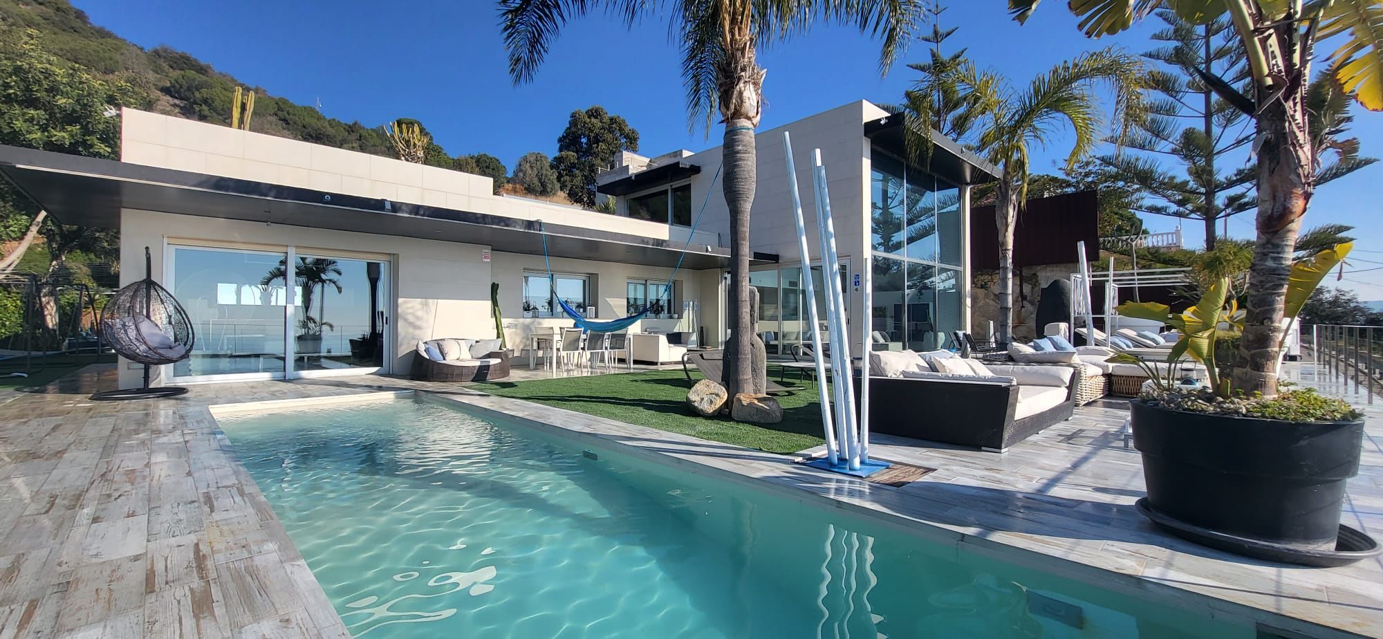 Facade and outdoor swimming pool. Areas for sitting and sunbathing on the lawn or on sun loungers.