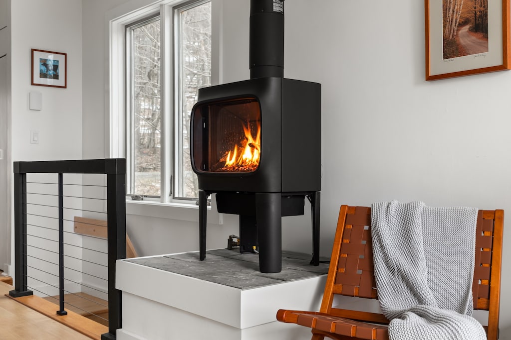 - Fireplace with modern design adds warmth to Airbnb experience   - Vacation rental offers cozy evenings with indoor fire seating   - Relax in comfort with wood burning stove and scenic window view